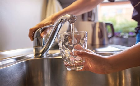 Cup of water being filled at kitchen sink
